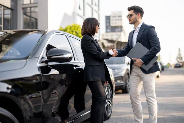 Business partners shaking hands beside a luxury vehicle in Greensboro, NC