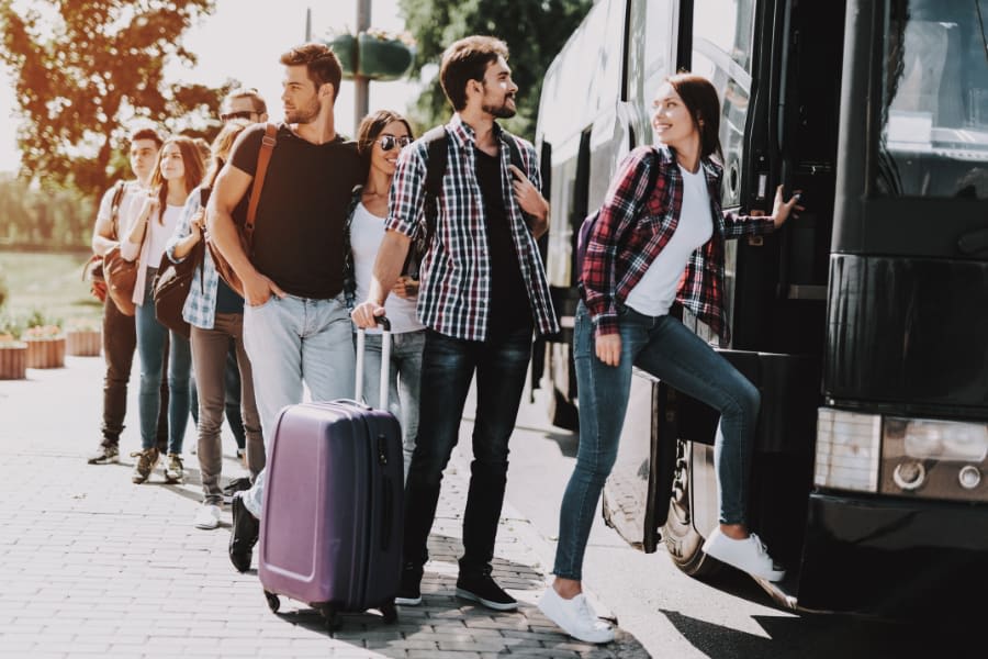 Group of five people standing near a luxury bus for concert transportation in Greensboro NC